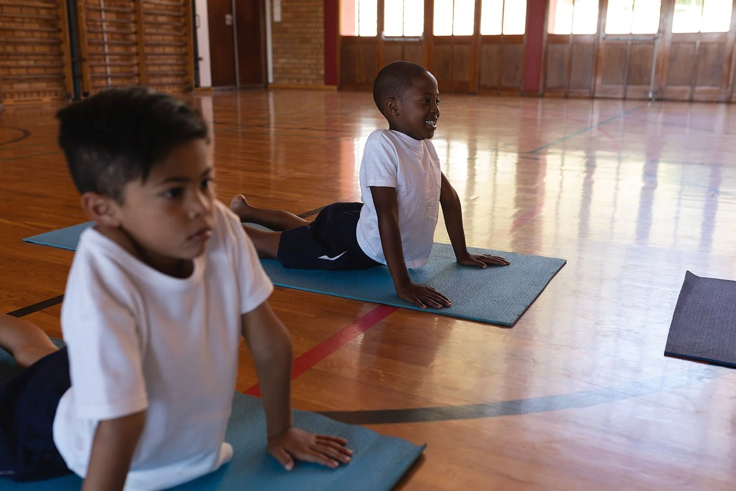 Children practicing yoga on mats in a gym.