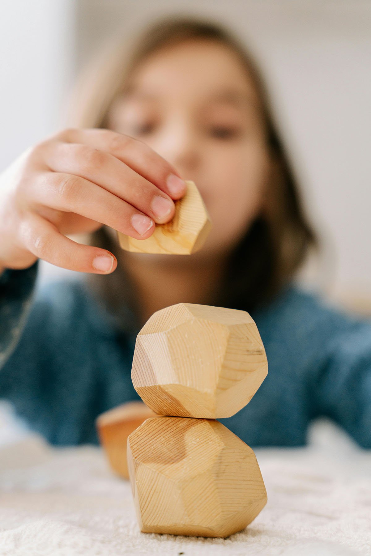 Child stacking wooden geometric blocks