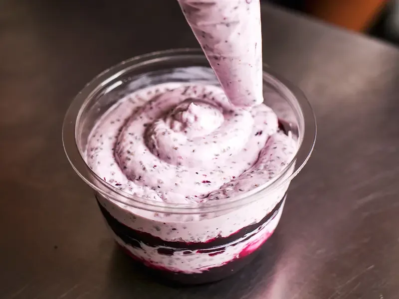Fresh berry dessert being piped into a cup, demonstrating how menu development services create innovative recipes and ensure menu development services deliver high-quality, appealing products for consumers.