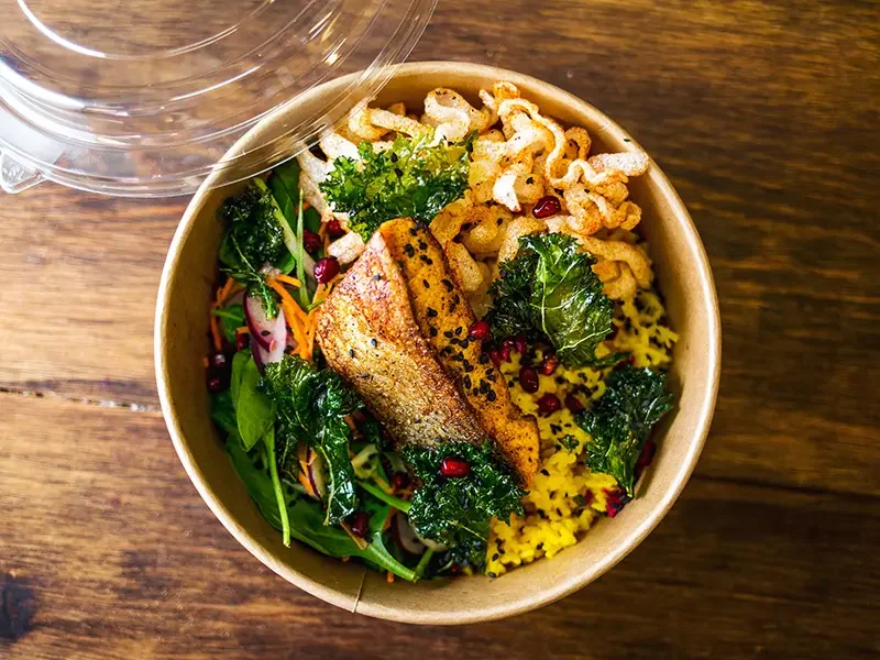 Colourful takeaway bowl with fish, rice, vegetables, and crispy toppings showcasing how menu development services create balanced, innovative, and appealing dishes tailored for modern consumer tastes.