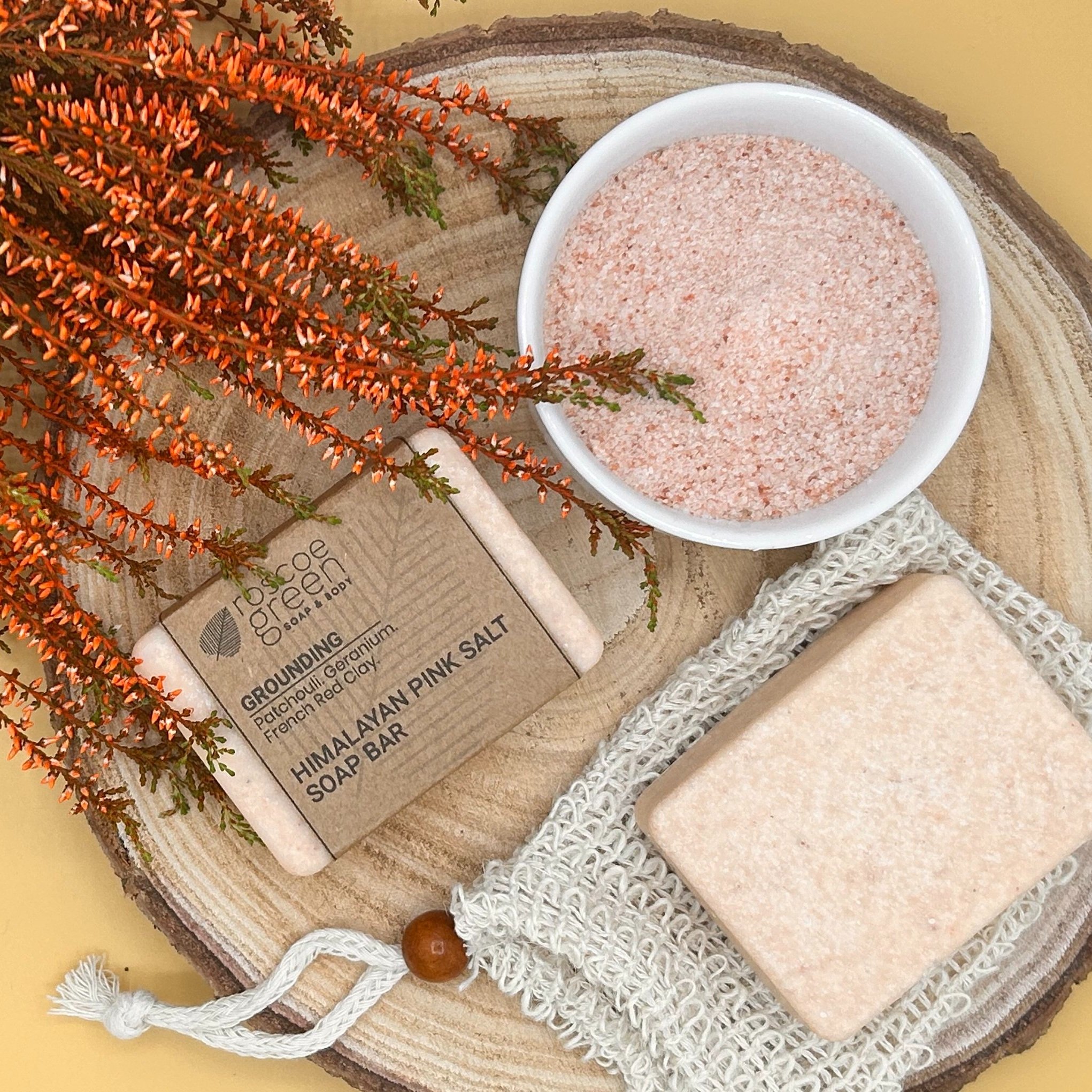 Patchouli, Geranium and French Red Clay - Himalayan Pink Salt Soap on a slice of wood and a bowl of salt.