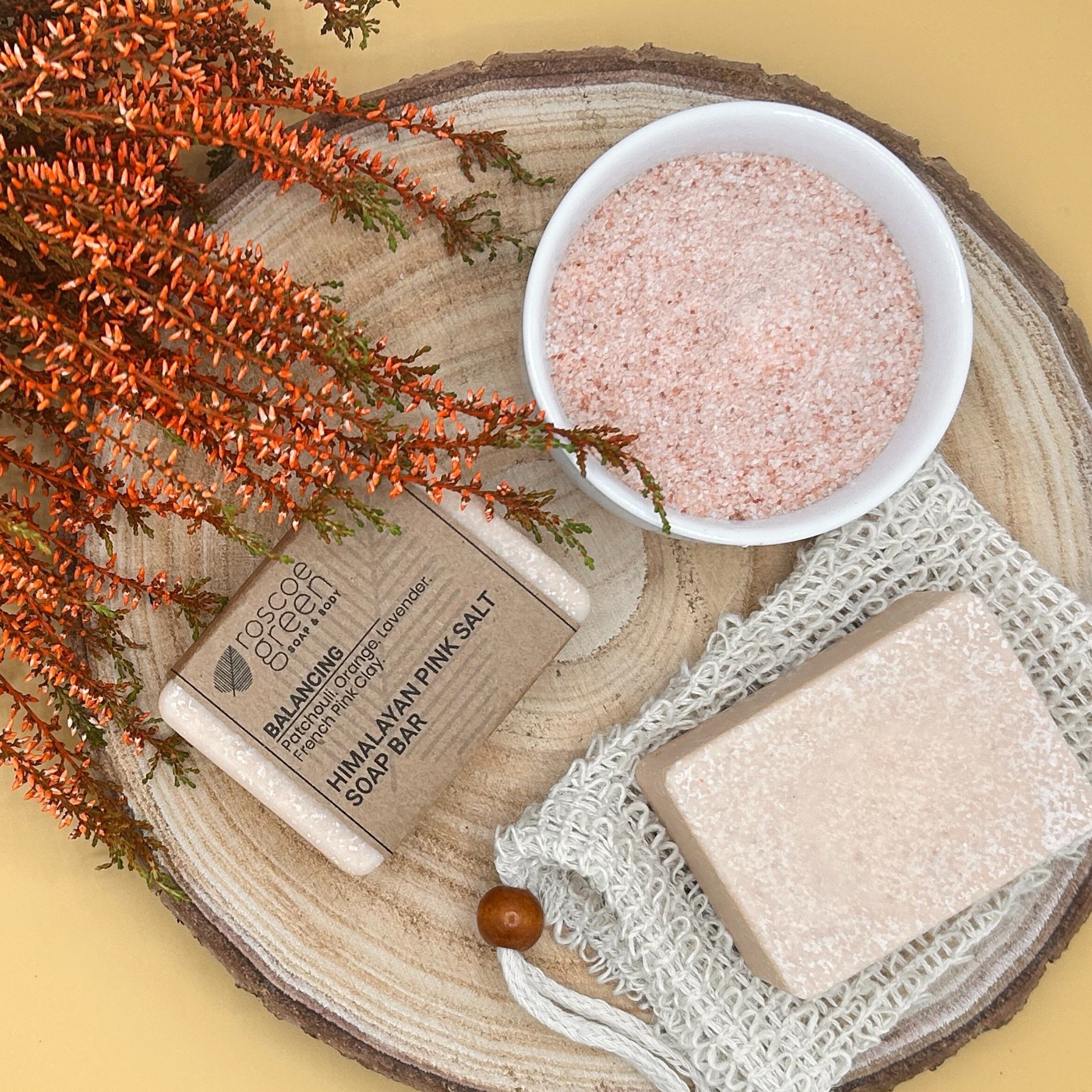 Patchouli, Orange, Lavender and French Pink Clay - Himalayan Pink Salt Soap on a slice of wood and bowl of salt. on a slice of wood and a bowl of salt.
