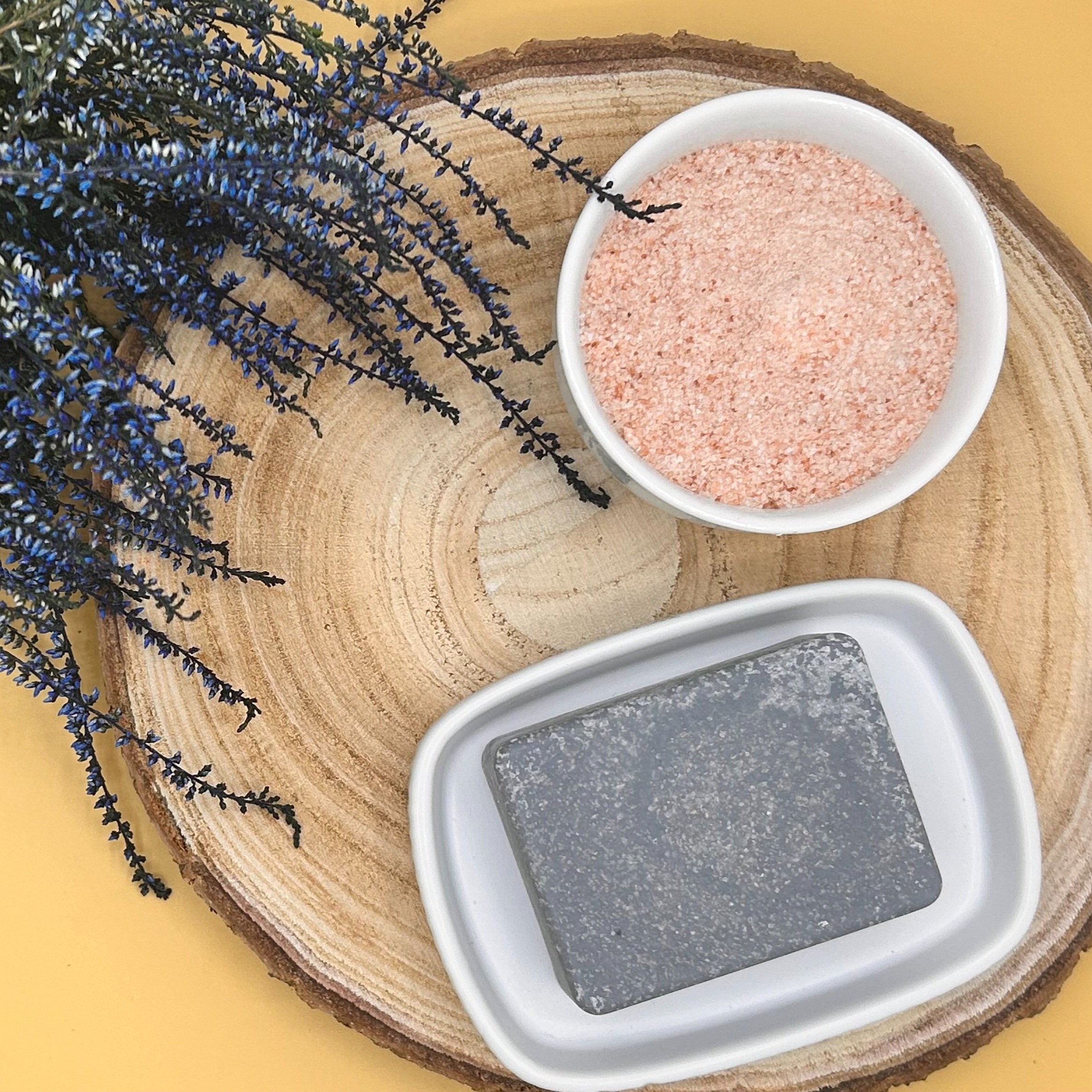 Eucalyptus, Peppermint and Activated Charcoal - Himalayan Pink Salt Soap Bar placed on a slice of wood with a bowl of salt.