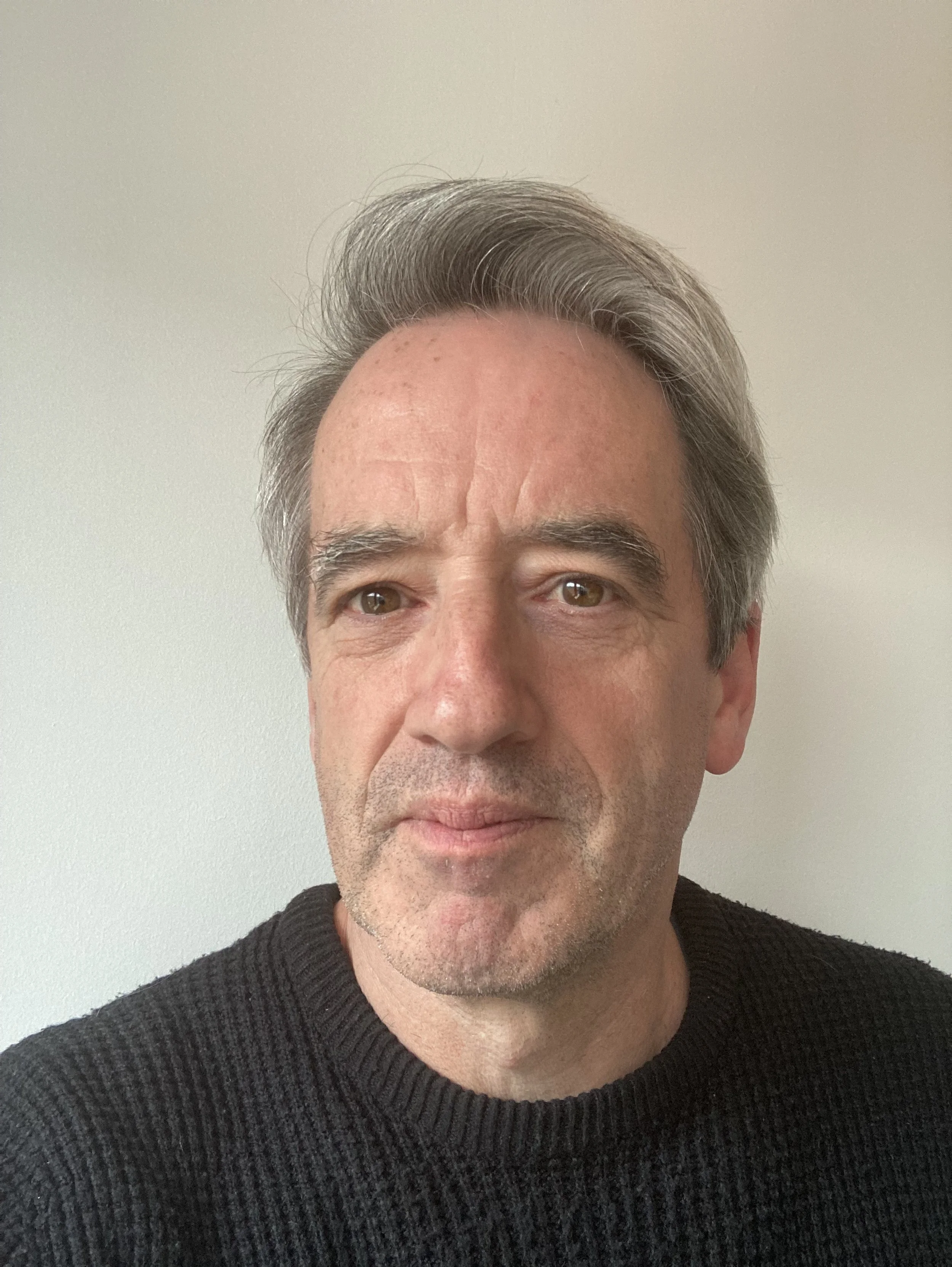 Person wearing a black sweater with light gray hair against a plain white background.