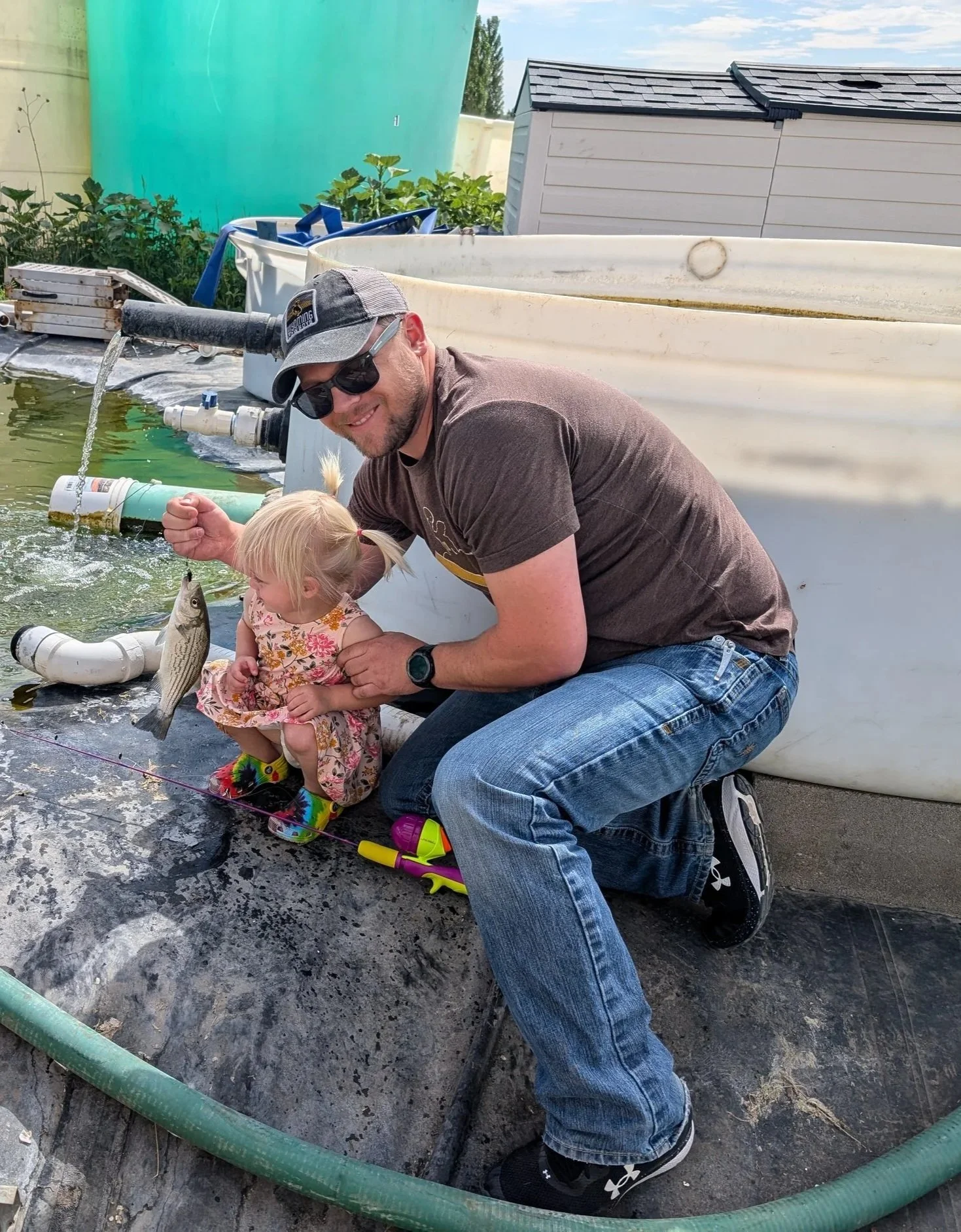 Anthony Murray of FML Aquaculture helping his daughter hold her first caught Wiper fish, demonstrating the joy of pond stocking.