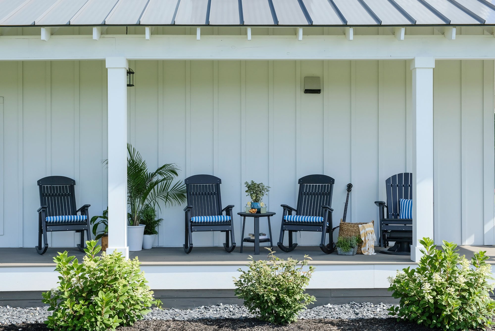 LuxCraft poly porch rocking chairs in black with blue striped cushions on a covered front porch