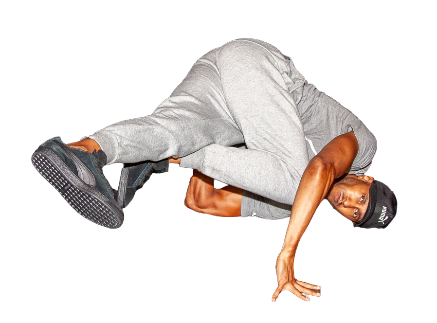 Daddy Long Leggs in gray sweatpants, gray t-shirt, and black cap performing a breakdance move called a shoulder style baby freeze on the floor utilizing his elbow rather than flat hand.