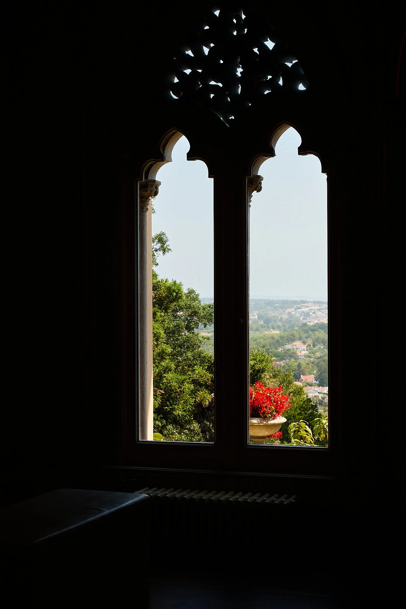 Ornate arched window overlooking a green countryside village