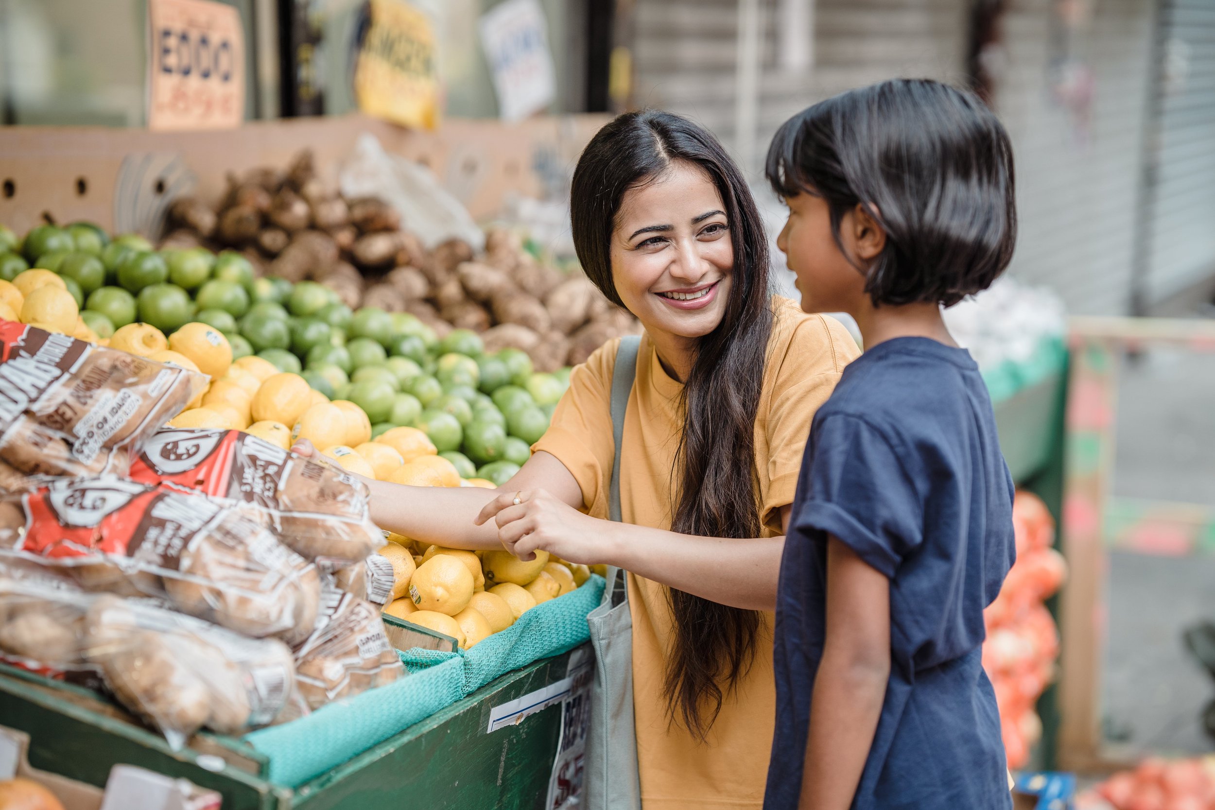 A photo of a mother and child choosing fruit at a store represents aligning their spending with their values and teaching those messages daily. 