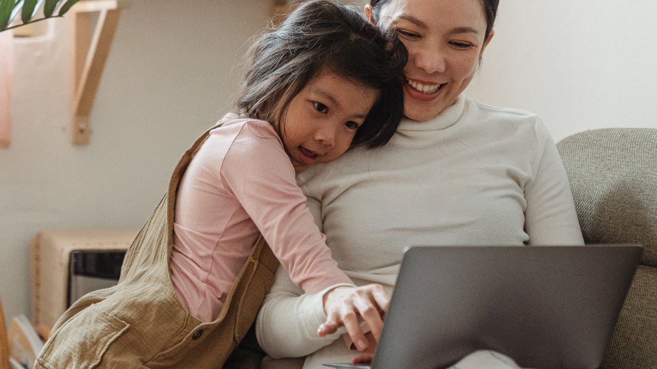 A photo of a Mom and daughter connected and looking at a computer looking at online shopping teaching needs vs wants.