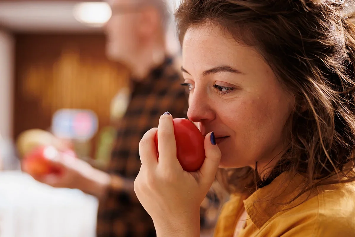 Consumer evaluating the freshness and aroma of a tomato as part of a fresh produce product testing programme focused on taste, quality, and sensory performance.