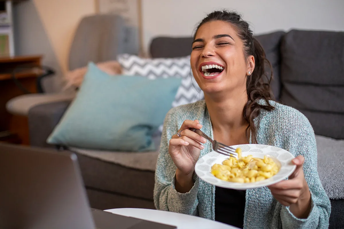 Smiling woman enjoying a meal while engaging online, representing how Consumer Closeness Research UK connects brands with authentic, everyday consumer experiences to inspire empathy, innovation, and stronger brand relationships.