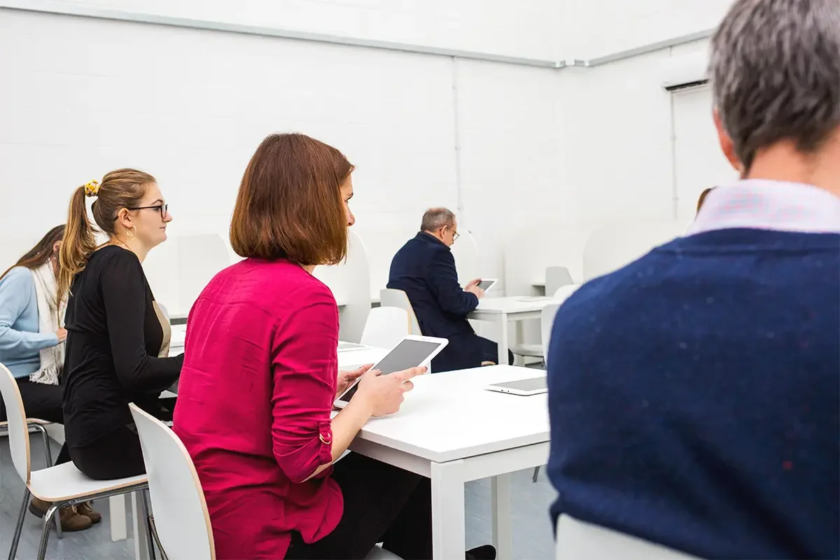 Participants seated in a testing facility using tablets during product testing and benchmarking, demonstrating how product testing and benchmarking gathers consumer insights in a controlled environment.