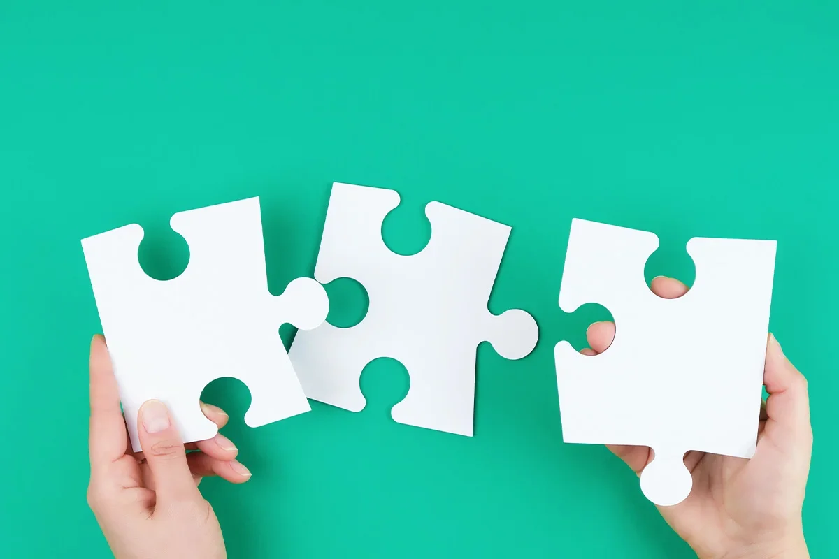 Hands connecting puzzle pieces to illustrate how Consumer segmentation research UK brings together data, insights, and strategy to form a complete understanding of target audiences and drive smarter business decisions.