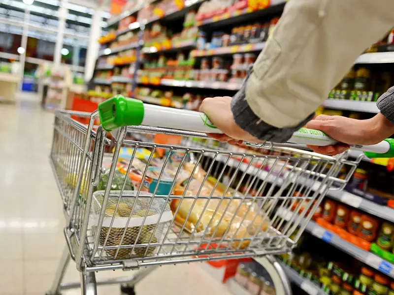 Shopper pushing a trolley through a supermarket aisle with groceries, illustrating how shopper behaviour research tracks shopping journeys, purchase patterns, and in-store decision-making through shopper behaviour research studies.