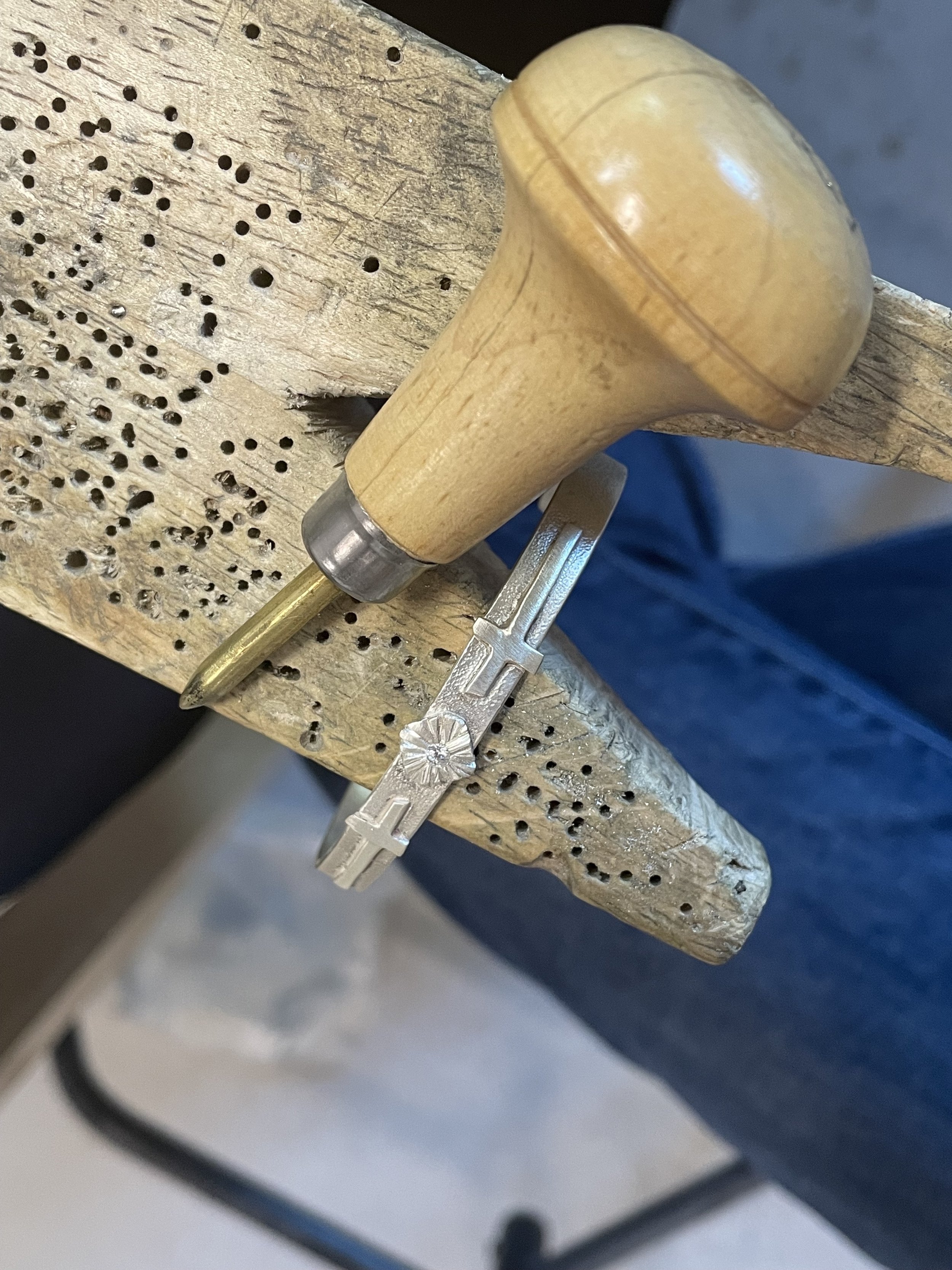 A custom-made burnishing tool alongside a finished jewelry piece featuring flush-set gemstone. Enroll in a class to learn the technique with precision and craftsmanship.
