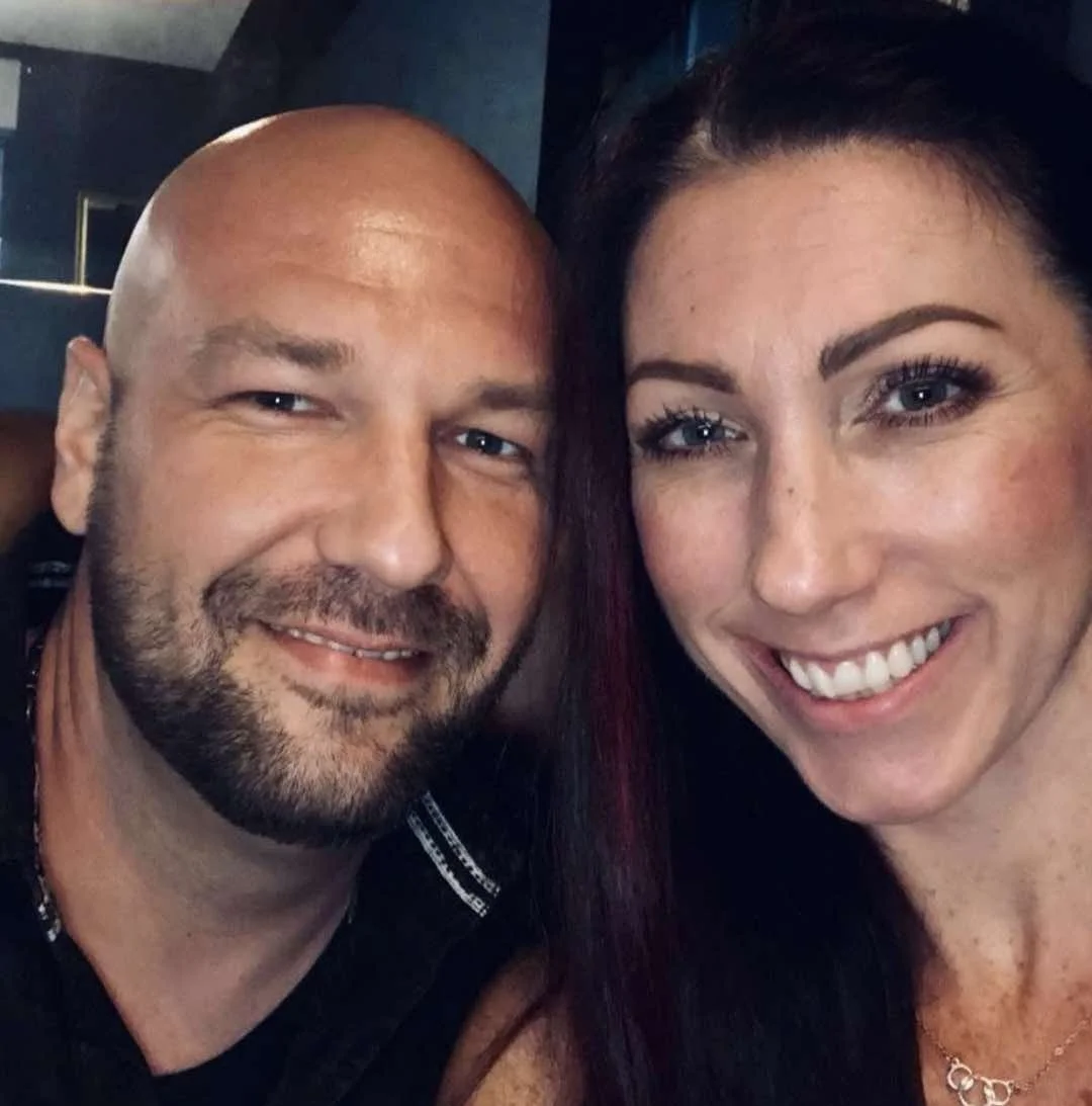 Close-up of a smiling man and woman taking a selfie indoors.