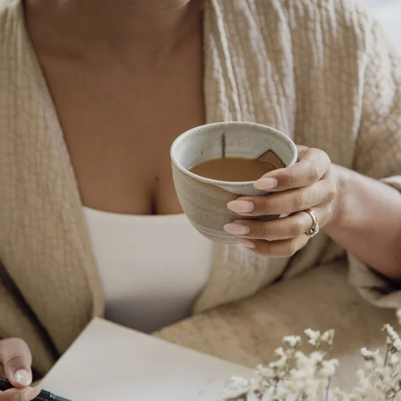 Woman sitting quietly in morning light reflecting during a season of transition and healing