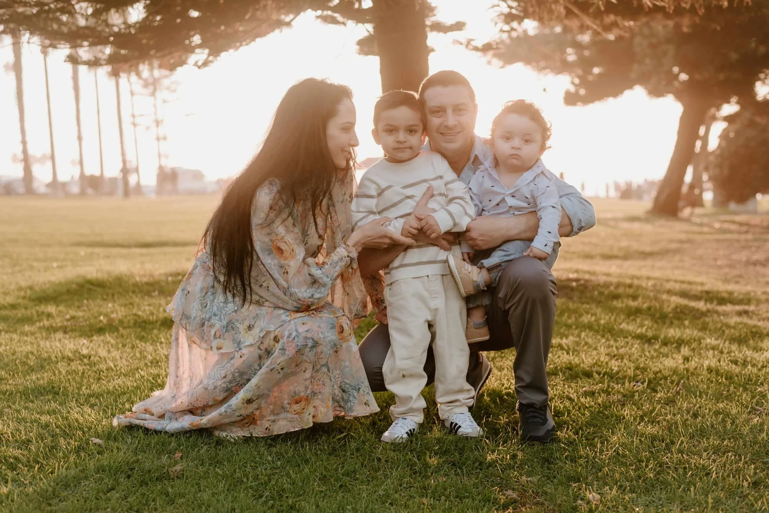 Family of four posing outdoors at sunset in a park, after working with Life Coach Dr. Mais Khourdaji, PhD in Ohio.