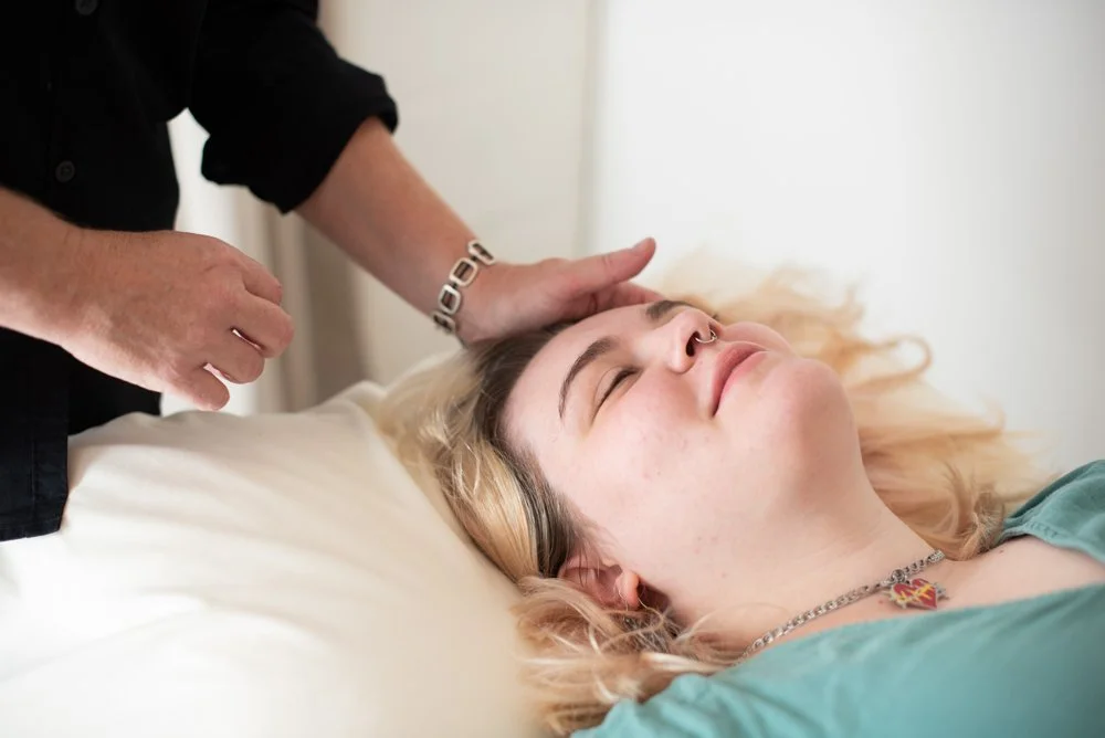 Person receiving a scalp treatment or massage while lying on a bed.