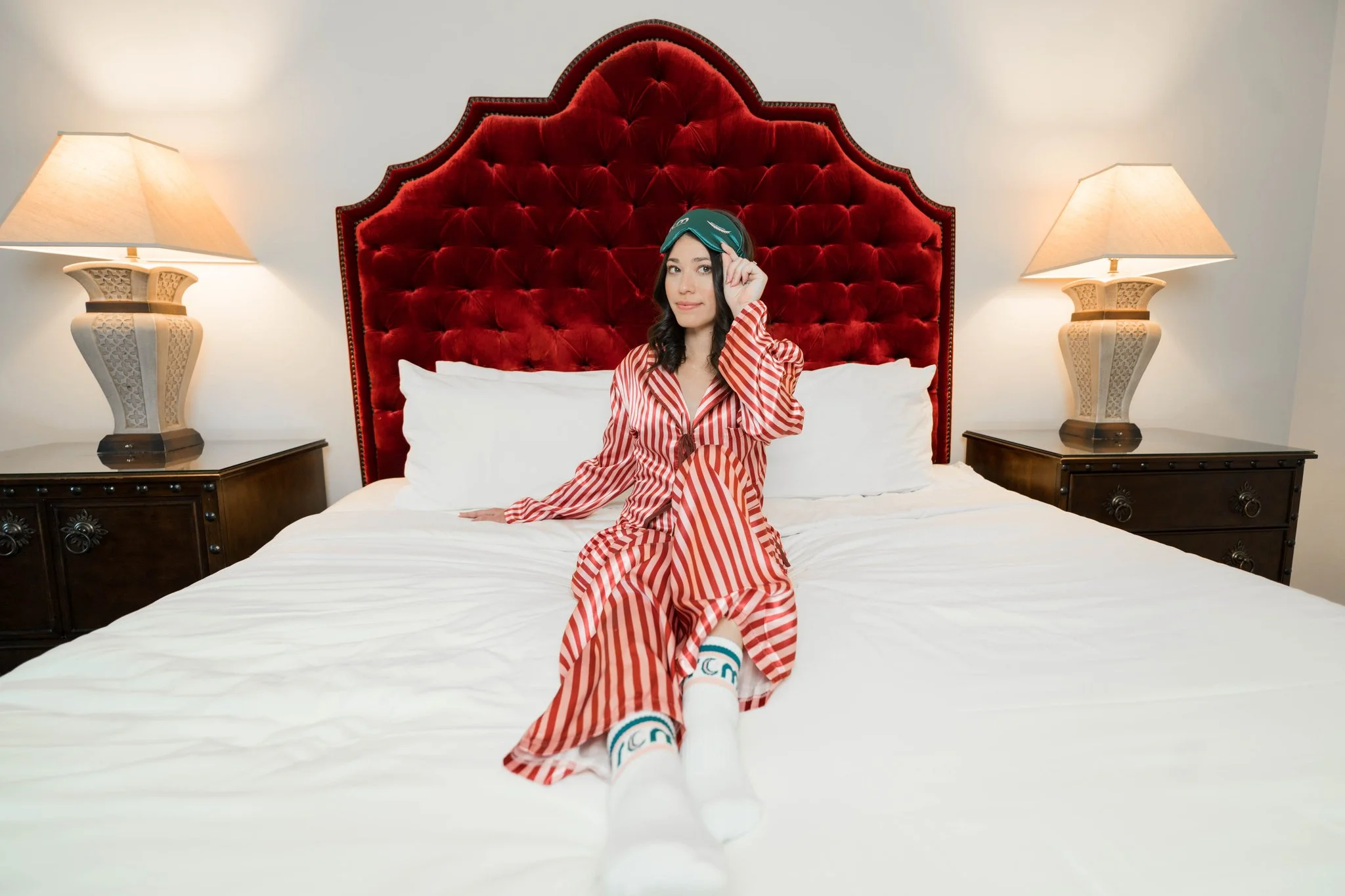 Tyler Miller of REM Real Estate Marketing lying on a bed in silk pajamas and REM-branded socks, smiling.