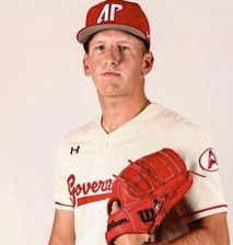 Young male baseball player in a white uniform with red details and a red cap, holding a red baseball glove.
