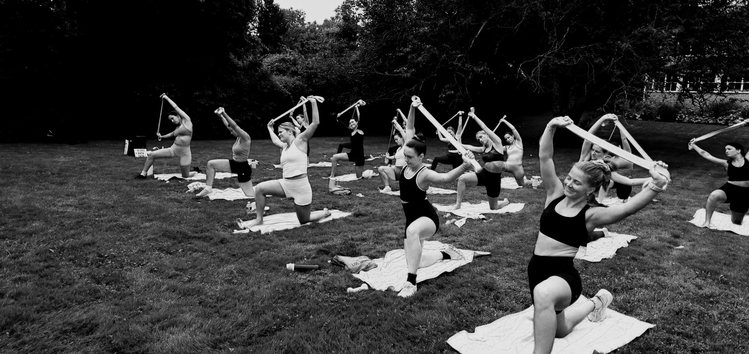young females stretching with bands in a group fitness class outside
