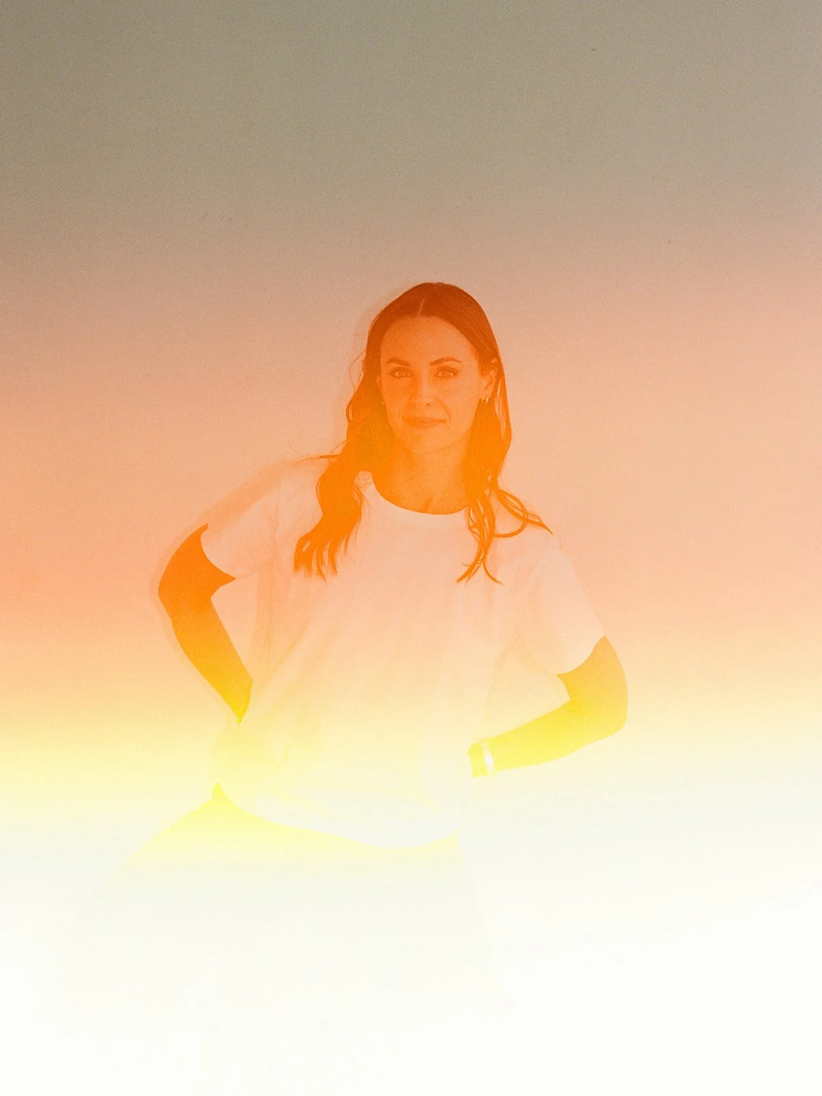 Sun drenched film portrait with a warm light leak, woman in a white t-shirt