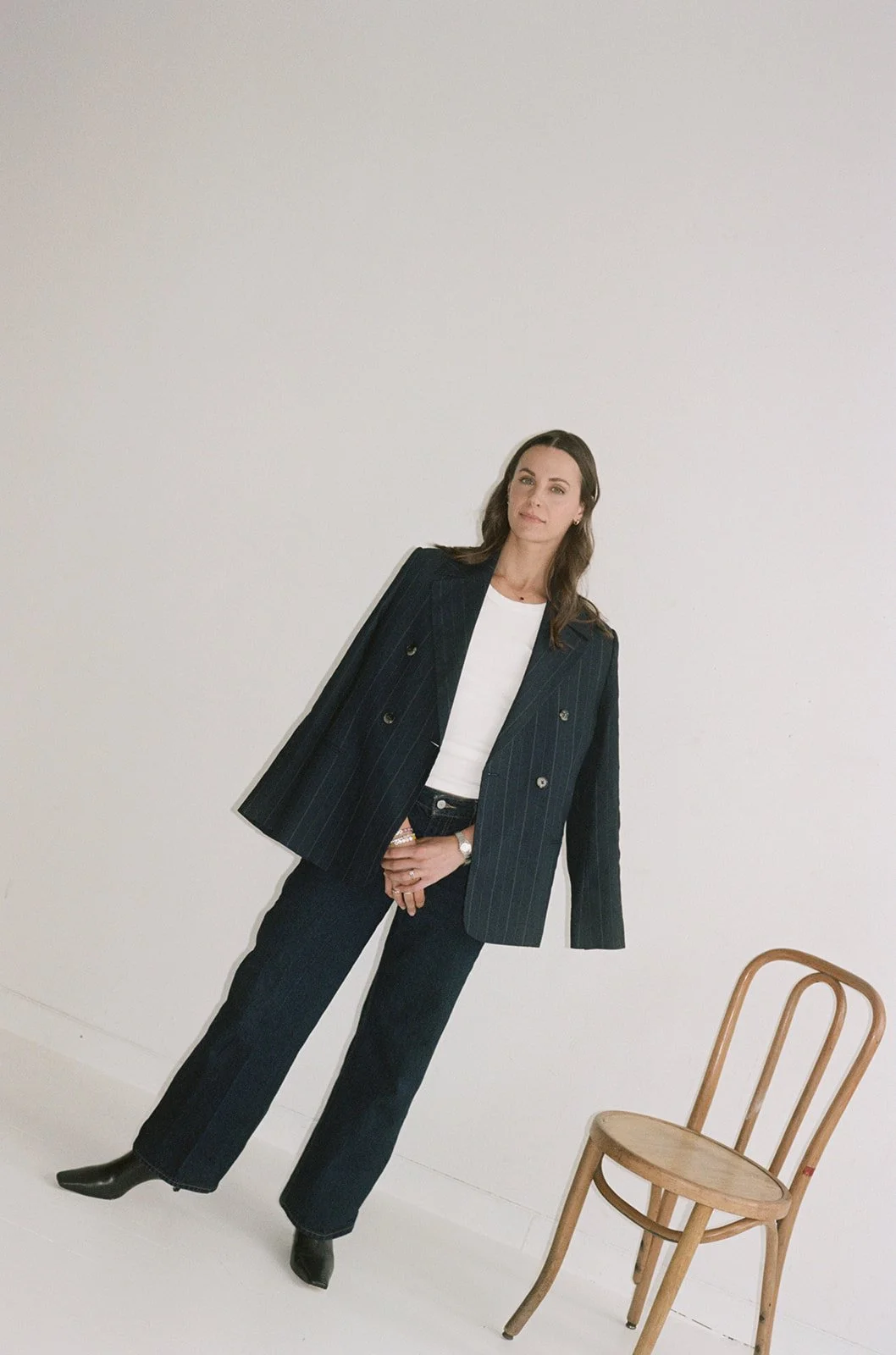 Full length film portrait of a woman in a matching pinstripe suit in a white studio