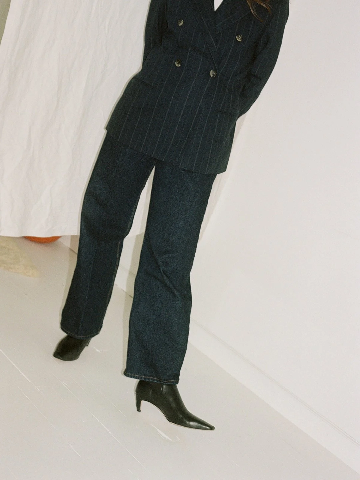Detail crop of a tailored pinstripe suit and pointed heel boots shot on film