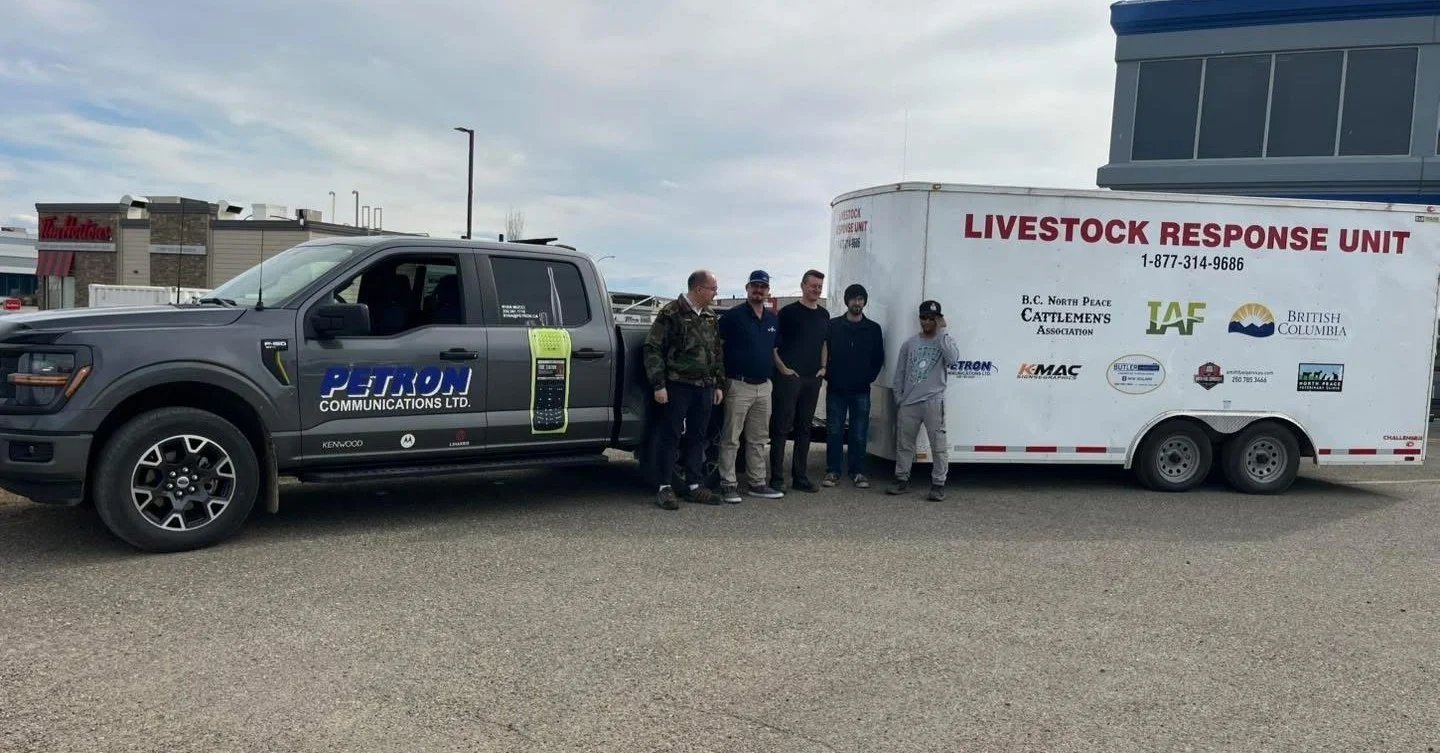 A group of five people standing near a truck with a trailer labeled 'LIVESTOCK RESPONSE UNIT' parked outdoors; a building and a Starbucks sign are in the background.