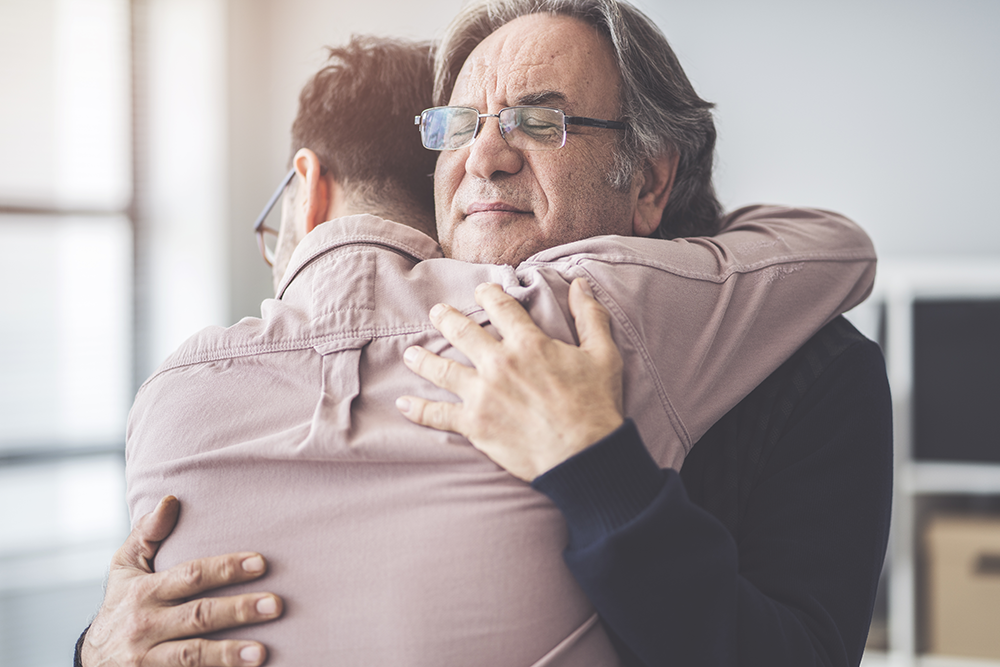 Two people hugging each other warmly in an indoor setting