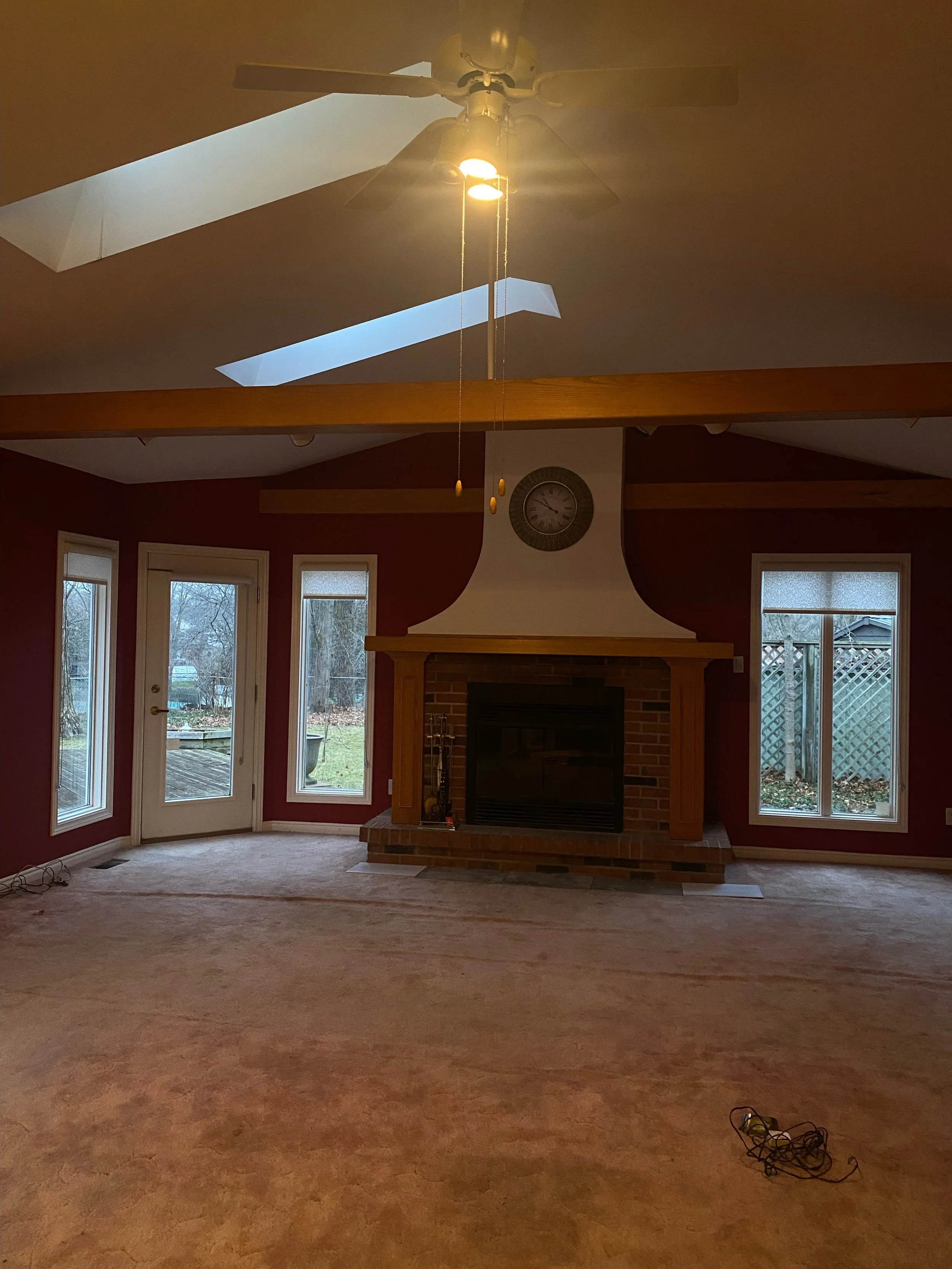 Before picture of living area in West London prior to renovation by Burcon Construction, featuring dark and shaggy pink carpet and dark red walls.