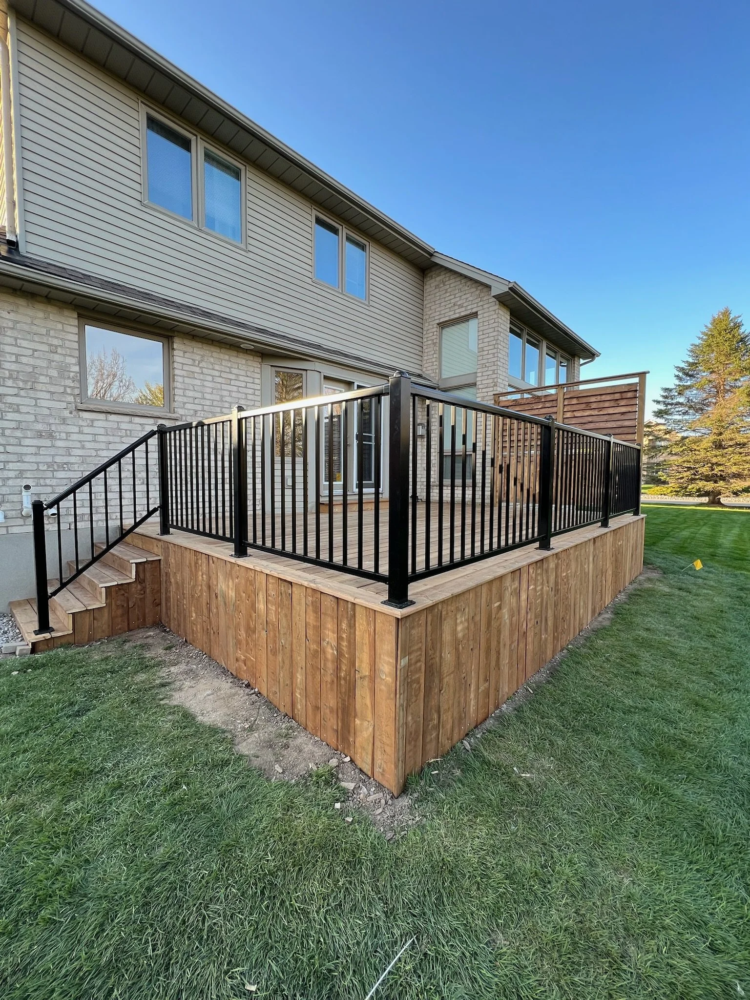 Completed deck in Kilworth by Burcon Construction, featuring black metal railings for safety and aesthetics.
