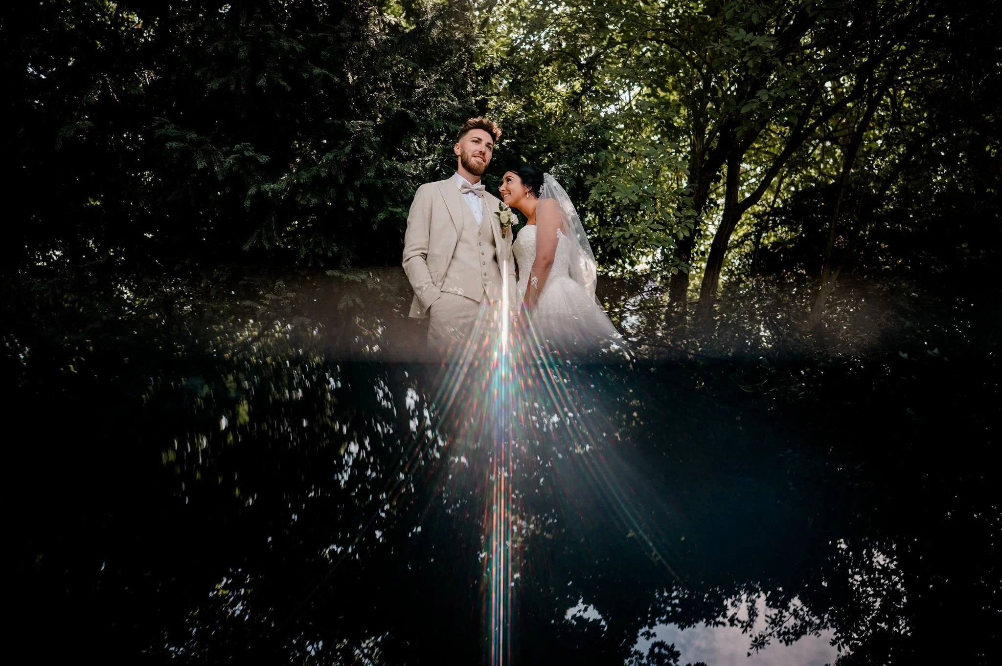 Een paar op hun huwelijksdag in een bos, lachend en gekleed in formele trouwkleding, met een onder water en boven water effect.