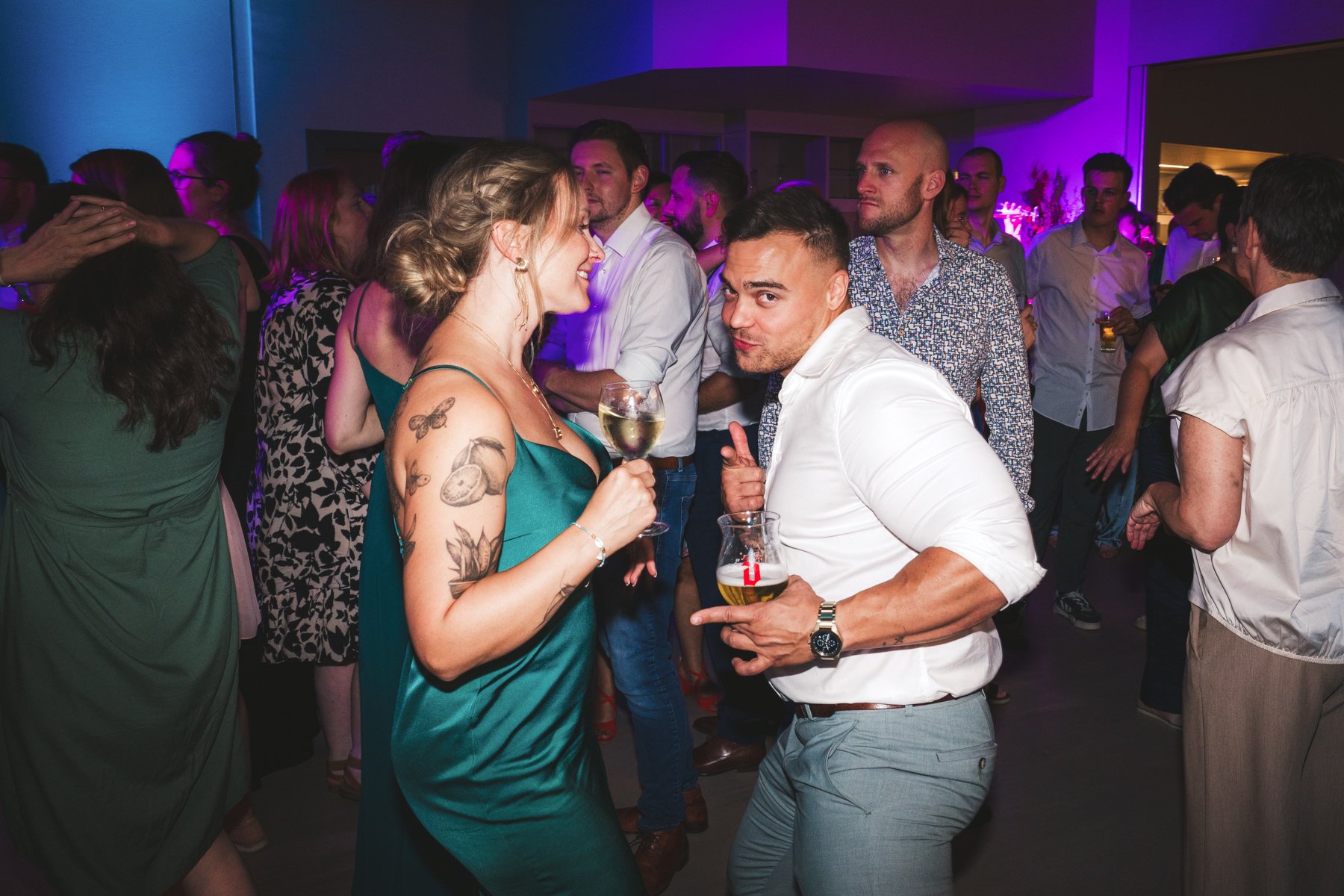 Mensen dansen en socializen op een feestje met kleurrijke verlichting.