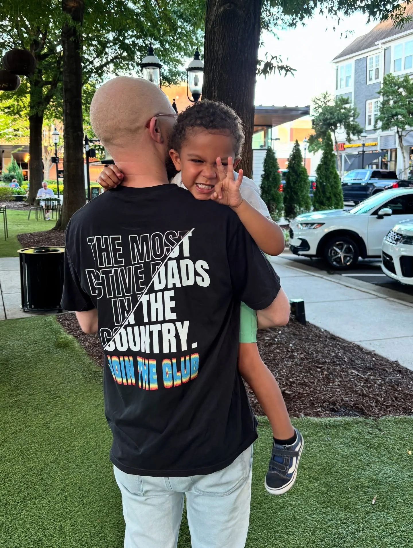 Father holding son, wearing Most Active Dads In the Country T-Shirt