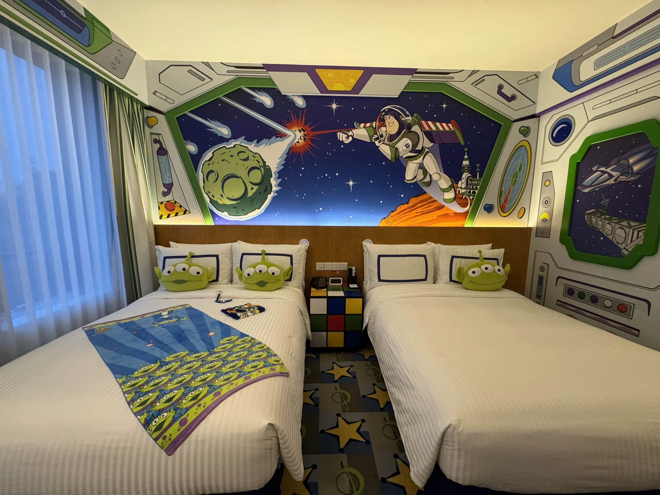 Beds with wall decorations and decorative Alien pillows in the Buzz Lightyear character room in Toy Story Hotel Shanghai Disney Resort