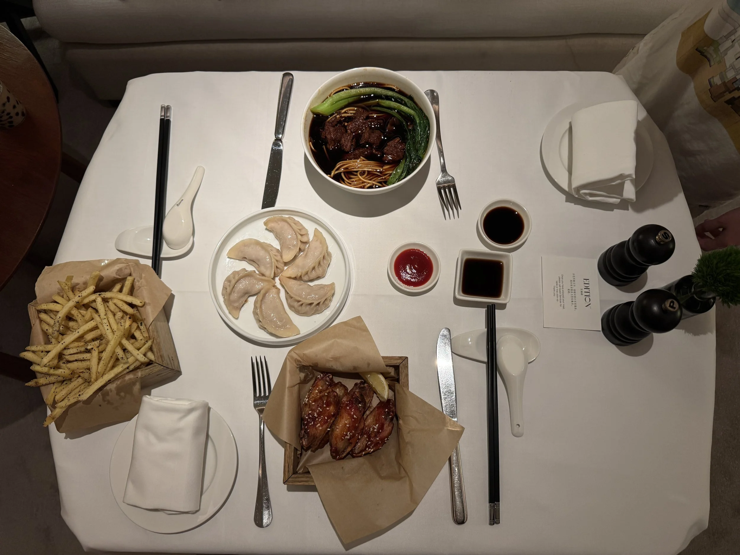 Room service table with fries, dim sum, wings, and noodles