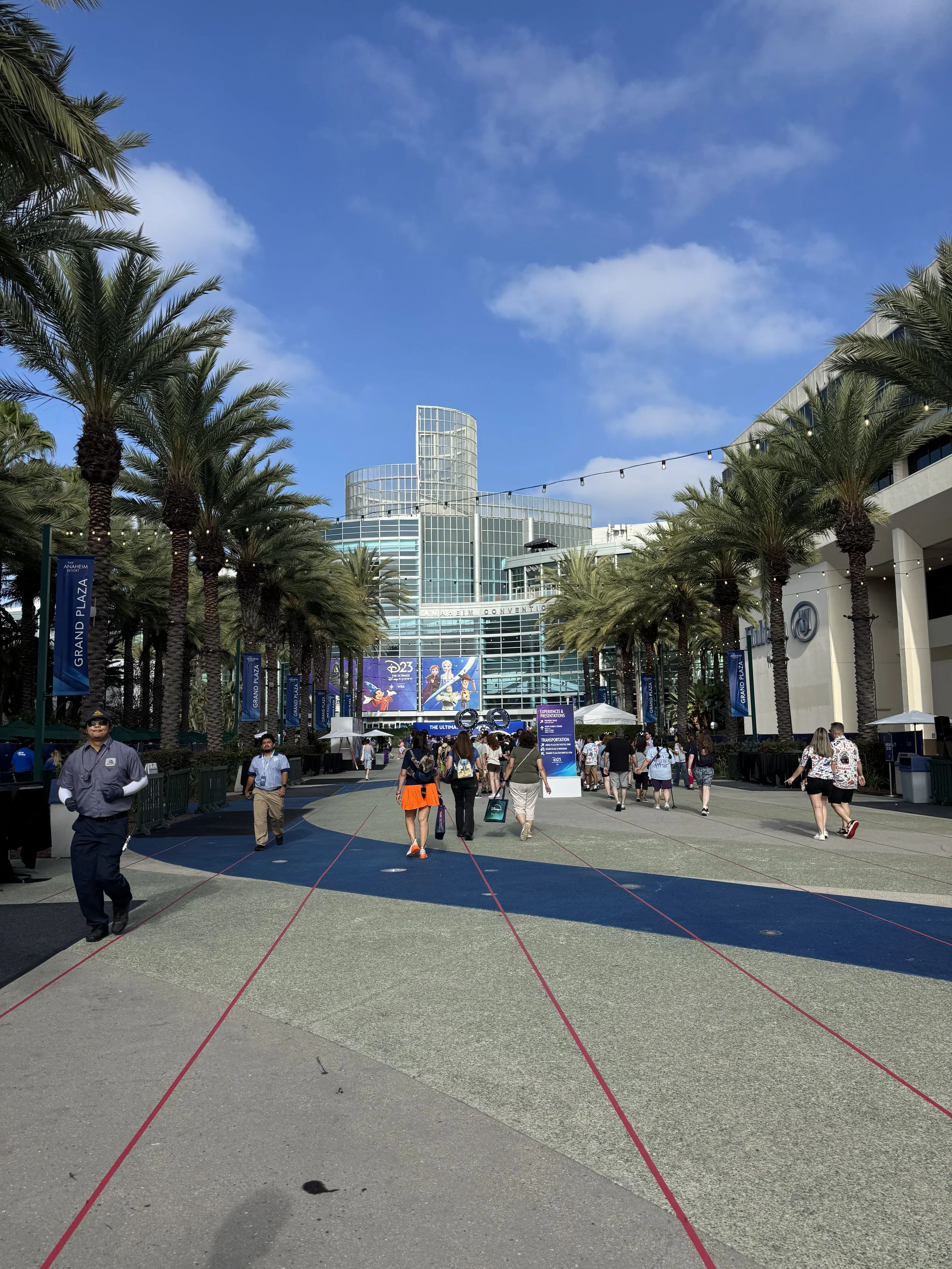 Walking toward the entrance of the convention center building with tape on the floor of queues but not a lot of people