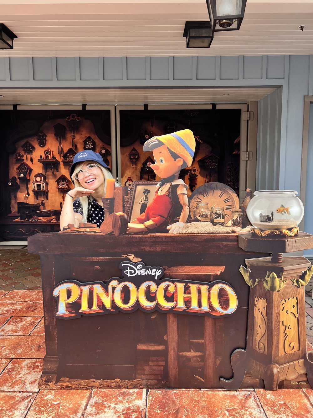  girl with a Disney+ bucket hat posing with a Pinocchio photo op set 
