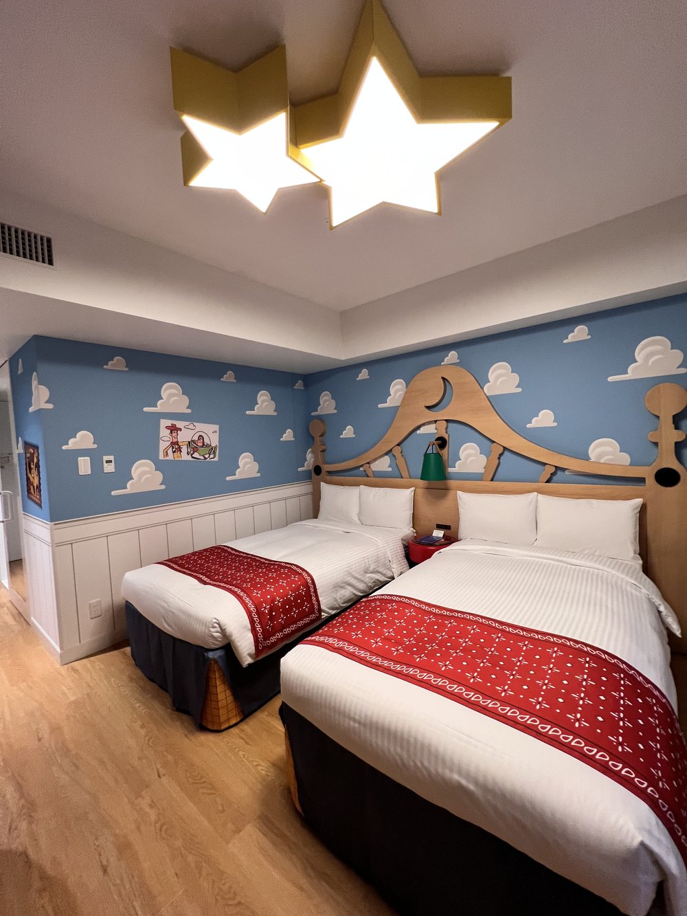  Zoomed out view of the Toy Story Hotel bedroom with two beds, star lights, and cloud wallpaper 