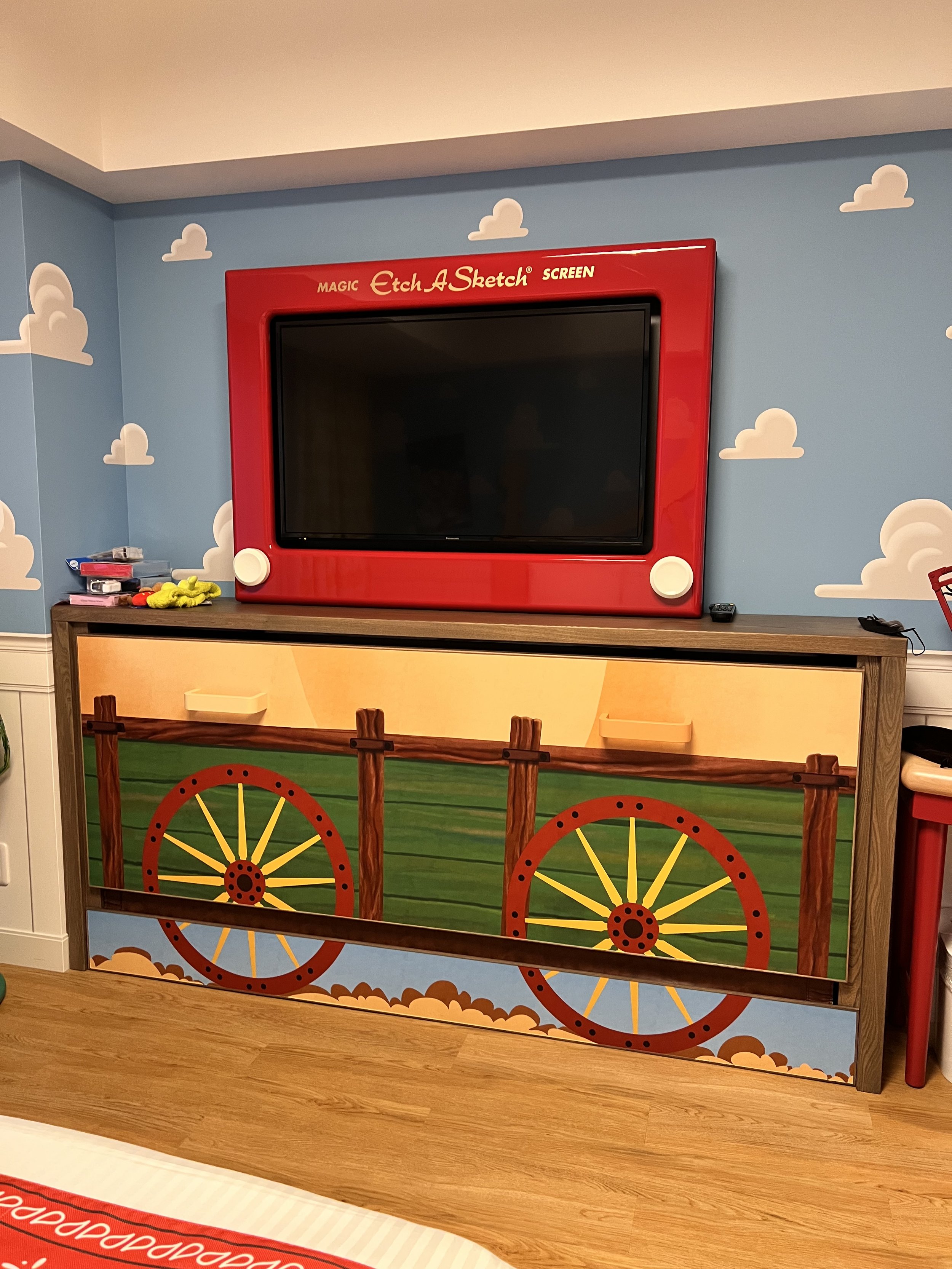  TV that looks like an etch-a-sketch on top of a brown cabinet that looks like a wagon 