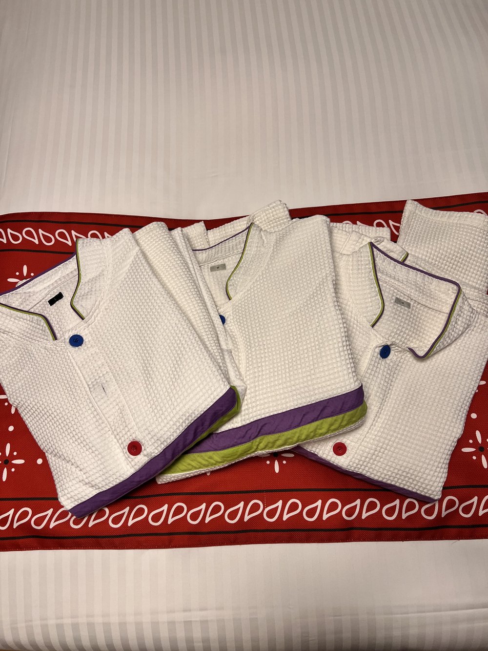  Three pajama sets that are white with purple and green stripes to look like Buzz Lightyear 