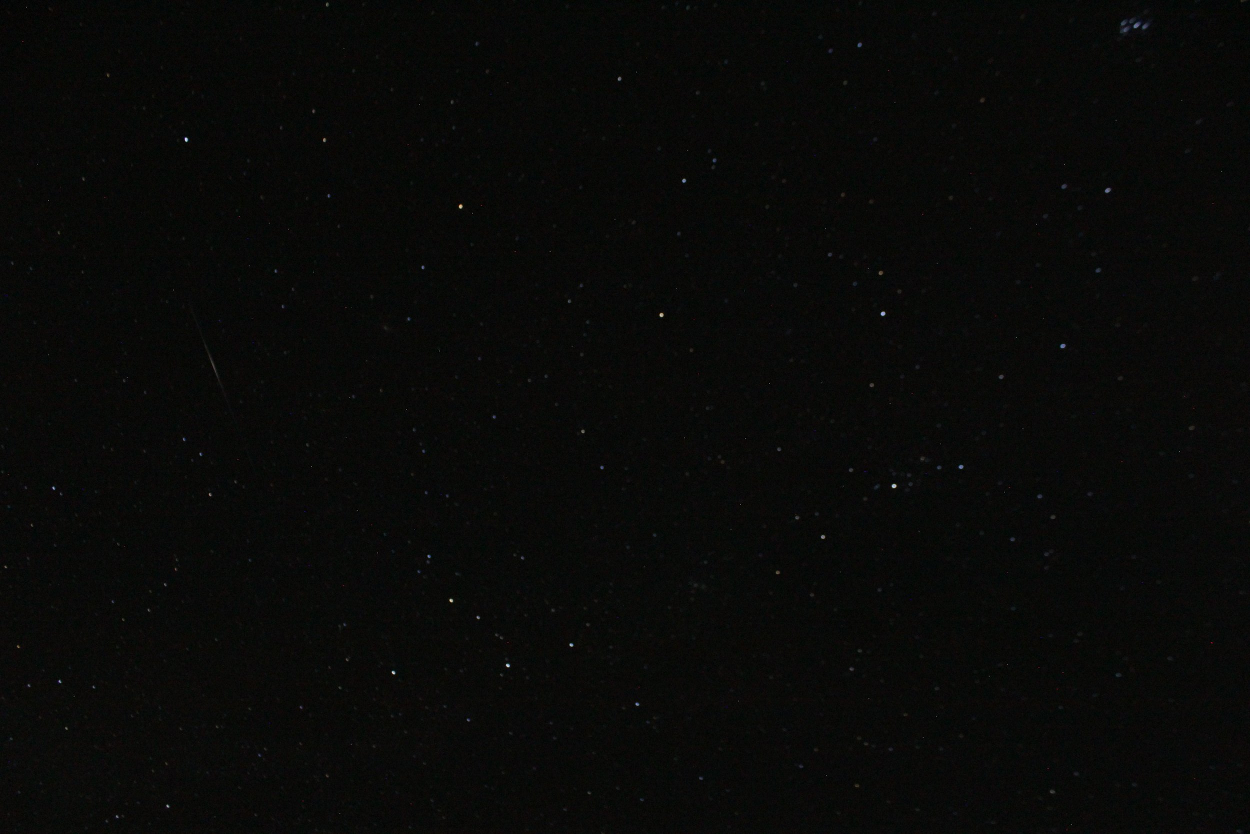 View of night sky stars with a streak of meteor on the left