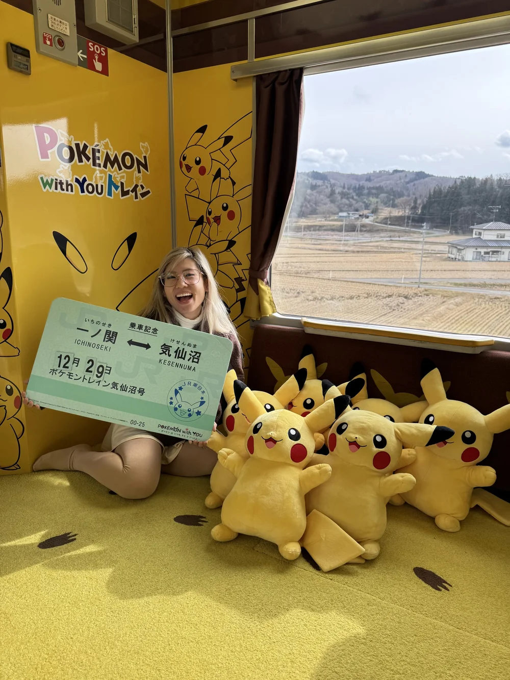  Holding a JR ticket prop next to a bunch of pikachu plushies 