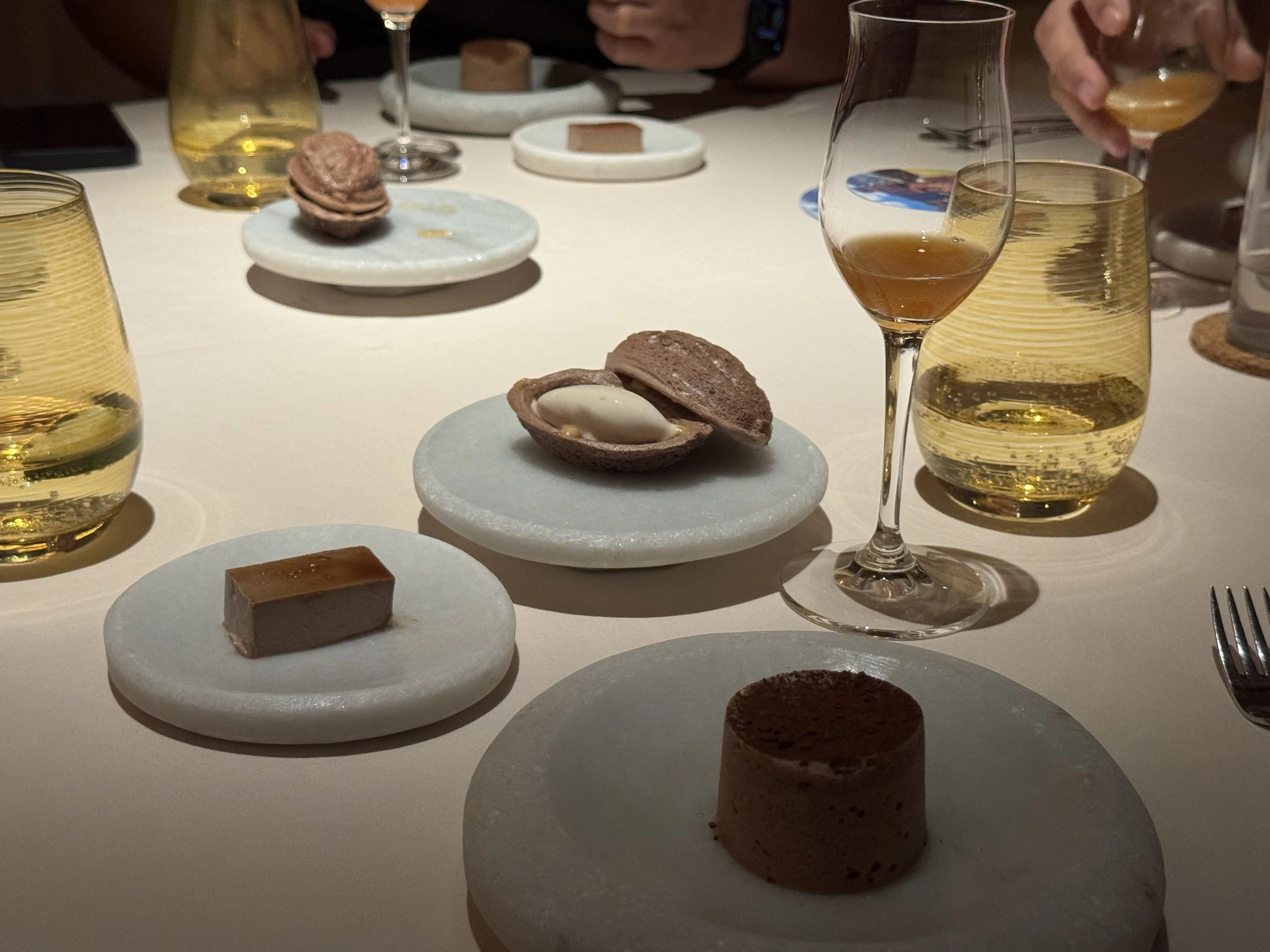 3 white stone plates with chocolate desserts - soufflé, mucilage, and ice cream in a cacao shaped rice crispy shell