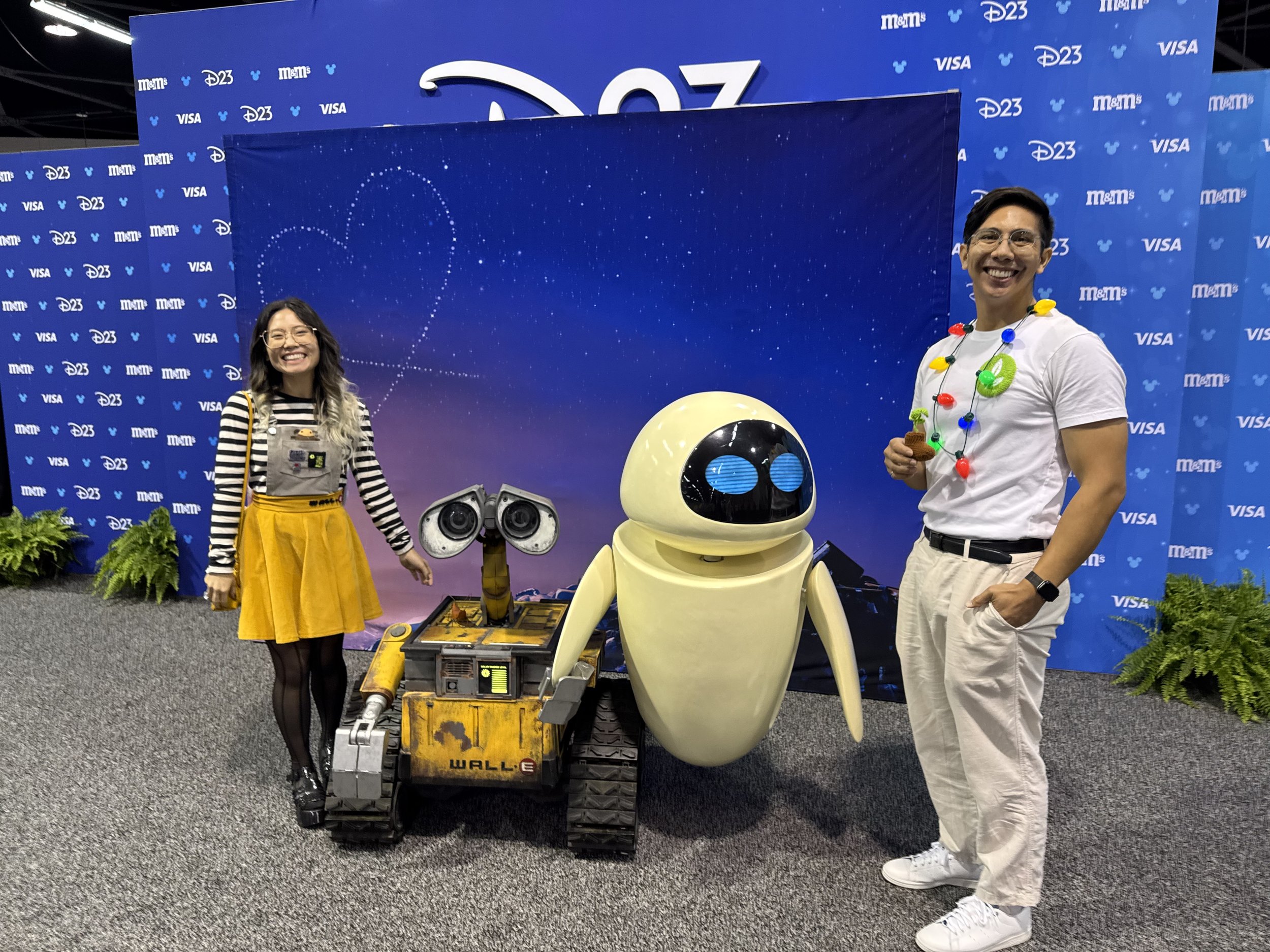 Wall-E and EVE robots between two people dressed as Wall-E and Eve