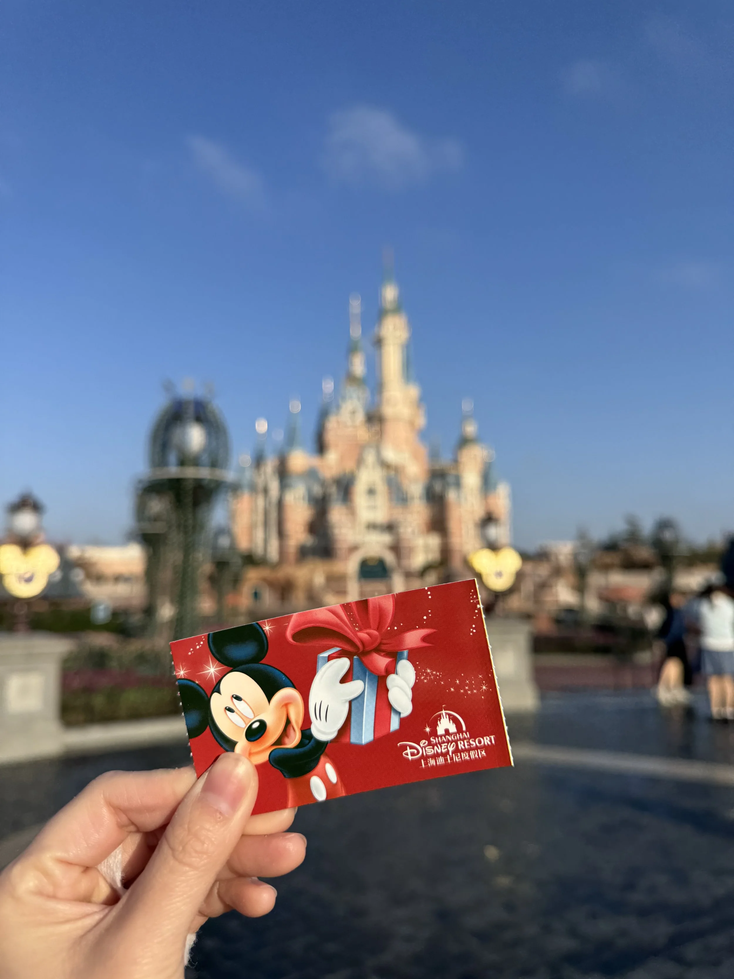 View of Shanghai Disneyland castle in the background with red Mickey admission ticket in the front