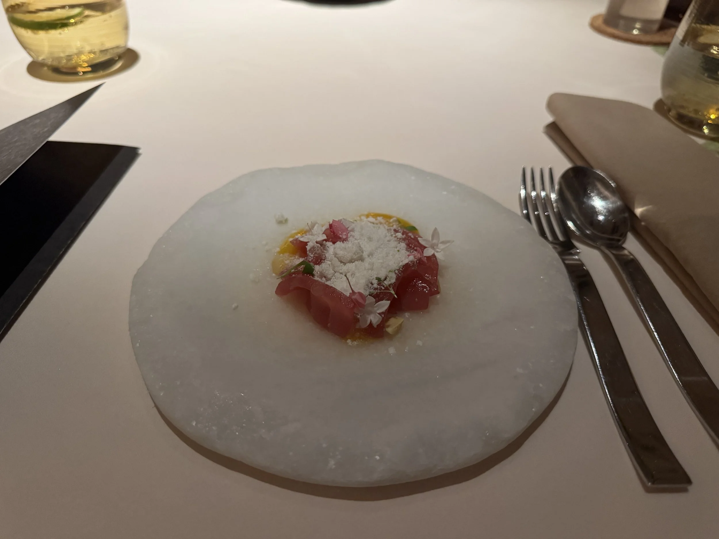 white stone plate with layered tuna sashimi topped with mango and coconut granita
